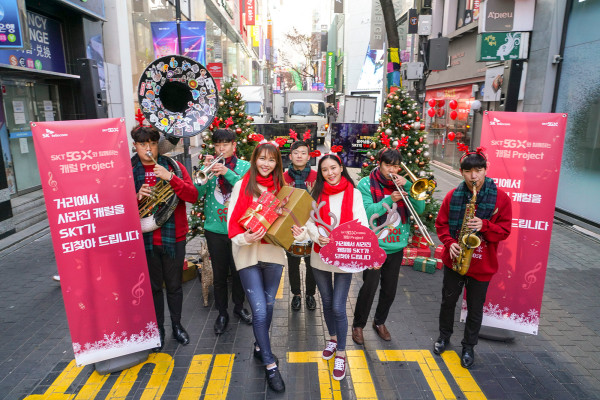 ▲19일 오전 서울 명동 한가운데에서 크리스마스 브라스밴드가 캐럴 공연을 하며 ‘캐럴이 돌아왔다’ 프로젝트를 알리고 있다. ⓒSK텔레콤