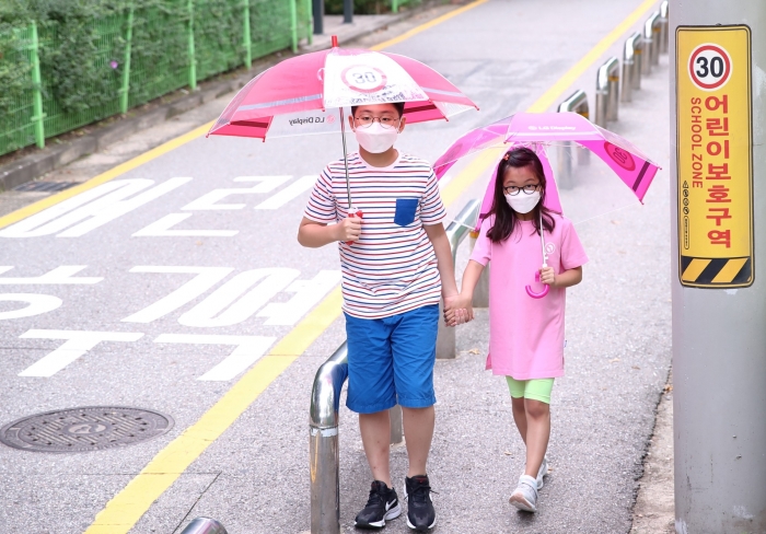 ▲어린이들이 LG디스플레이가 준비한 '투명 안전 우산'을 쓰고 가는 모습. ⓒLG디스플레이