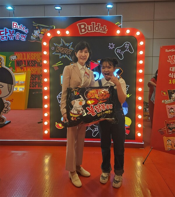 ▲하노이에서 진행된 K-Food 페스티벌 삼양식품 부스 앞에서 삼양식품 김정수 부회장(왼쪽)과 베트남 인플루언서 자한(N.ZaHan)이 사진을 촬영하고 있다. ⓒ삼양식품