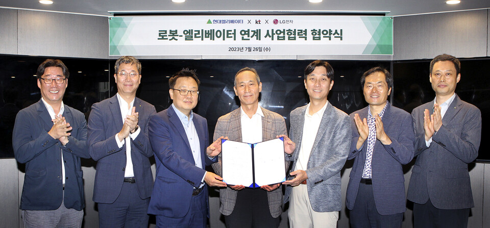 ▲(왼쪽 세번째부터) 이상호 KT AI로봇사업단장, 도익한 현대엘리베이터 서비스사업부문장, 노규찬 LG전자 로봇사업담당을 비롯한 관계자들이 지난 26일 서울 종로구 현대그룹 빌딩 비전스튜디오에서 ‘로봇-엘리베이터 연계 사업협력 협약식’에서 MOU 체결 후 기념 사진을 촬영하고 있다. ⓒKT