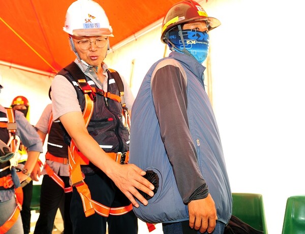 ▲방성종 SK에코플랜트 최고안전책임자(왼쪽)가 현장 근로자에게 선풍기 바람이 나오는 조끼를 착용해주고 있다. ⓒSK에코플랜트
