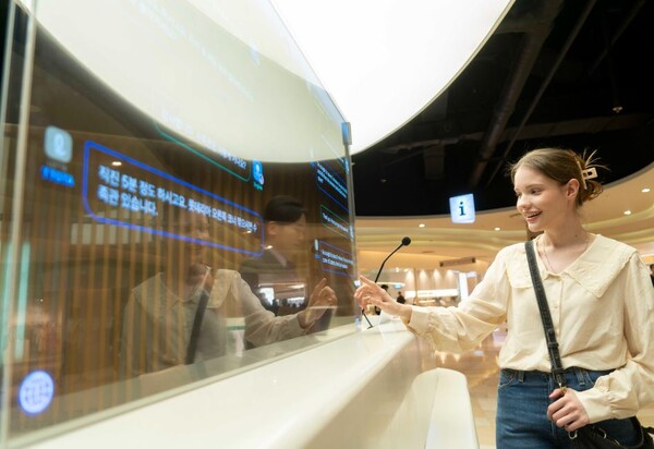 ▲에비뉴엘 잠실점 1층과 롯데월드몰 지하 1층 안내데스크에 설치된 ‘트랜스 토커’를 외국인 모델이 활용하고 있는 모습. ⓒSK텔레콤