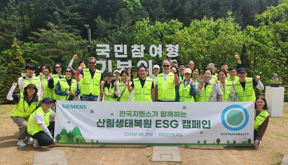 ▲한국지멘스 임직원들이 지난 29일 강원 춘천시에 있는 국립춘천숲체원에서 ‘산림생태복원 ESG 캠페인’을 진행한 뒤 기념 사진을 촬영하고 있다. 프랭크 짐머만 한국지멘스 수석부사장 겸 최고재무책임자((앞줄 왼쪽 다섯번째) ), 정하중 한국지멘스 대표이사(사장, 앞줄 왼쪽 여덟번째), 티노 힐데브란트 한국지멘스 선임부사장 겸 디지털인더스트리 부문장(앞줄 왼쪽 아홉번째). ⓒ한국지멘스