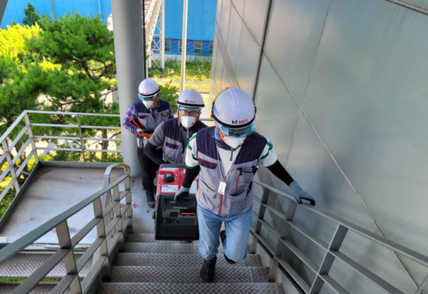 ▲(포스코와 이동통신 3사가 지난 13일 광양제철소에서 진행한 재난 대비 비상대응훈련에서) 기술 인력들이 비상발전기를 들고 공장 계단을 오르고 있다. ⓒ포스코