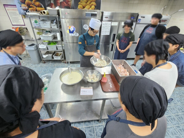 ▲BBQ 치킨대학에서 진행한 정직원 채용연계형 진로캠프에 참석한 자립준비청년들이 BBQ 황금올리브 치킨 조리 체험을 위해 만드는 과정을 배우고 있다. ⓒBBQ