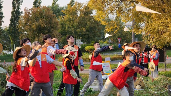 ▲SK이노베이션 계열 구성원들이 물에 녹는 종이에 씨앗을 담은 ‘꽃씨 비행기’를 생태교란식물 제거 자리에 던지고 있다. ⓒSK이노베이션