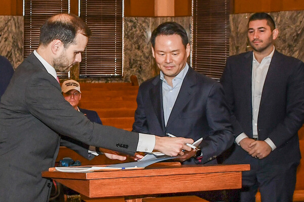 ▲지난 달 27일(현지시각) 미국 텍사스주 존슨 카운티(Johnson County) 지방법원에서 진행된 파리바게뜨 제빵공장 투자 인센티브 조인식에서 허진수 SPC그룹 사장이(가운데) 서명을 하고 있다. ⓒSPC그룹