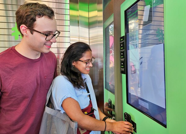 ▲(사진 오른쪽부터) 미국인 탄비(Tanvi)씨와 러셀(Russell)씨가 올리브영 명동 타운에 마련된 벤딩머신으로 글로벌몰에 가입하는 모습. ⓒCJ올리브영