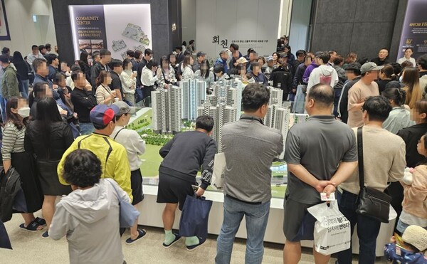 ▲'회천중앙역 파라곤' 견본주택을 찾은 관람객들이 단지모형도를 살펴보고 있다. ⓒ라인그룹